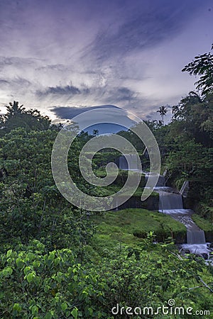 Merapi volcano with lenticular cloud on the peak of mountain with terraced waterfall Stock Photo