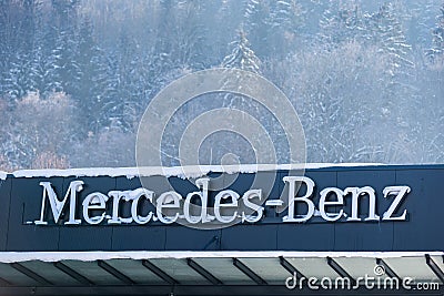 Mercedes Benz car brand logo on dealership showroom covered with snow. Editorial Stock Photo