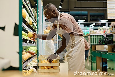 Merchandiser putting fresh fruits on shelves Stock Photo