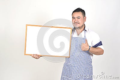 Merchant Asian man in white and blue apron to holding blank white broad for put some text or wording for present advertising Stock Photo