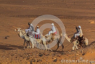 MEROE, SUDAN - MARCH 4, 2019: Locals ride camels near the pyramids of Meroe, Sud Editorial Stock Photo