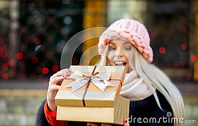 Merry blonde girl wearing knitted cap and warm coat, holding gif Stock Photo