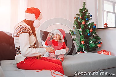 Merry Christmas and Happy New Year. Picture of happy kid sitting on sofa and hold white small round sweet. She looks at Stock Photo