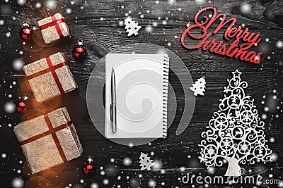 Merry Christmas composition with decorations gift, blank notepad and fir-wooden toy on black background Stock Photo