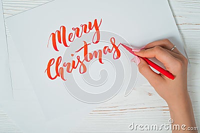 Merry Christmas congratulations. Calligrapher writes with red ink on white card. Calligraphy. Ornament font. The art of Stock Photo