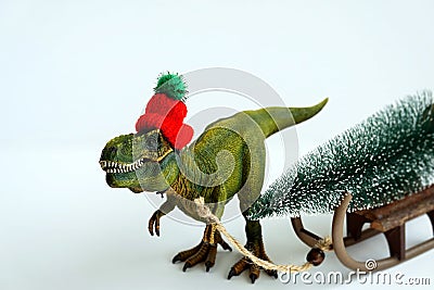Merry Christmas - funny toy t-rex dinosaur pull the sleigh with the Christmas tree on it. Stock Photo