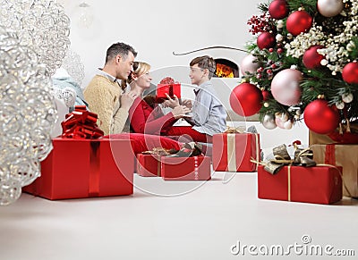 Merry christmas, happy family stay at home, parents giving the gift to their child near the illuminated and decorated tree, joyful Stock Photo