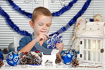 Merry Christmas and happy holidays!A boy painting a snowflake. Child creates decorations for Christmas interior. Stock Photo