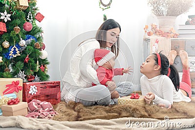 Merry Christmas and Happy Holidays! Cheerful mom and her cute daughters playing and have fun together Stock Photo