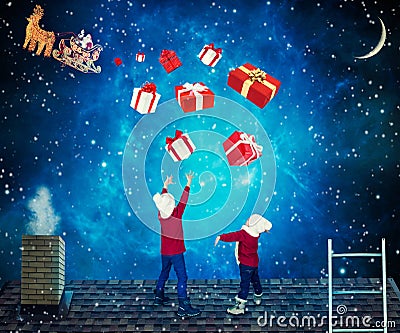 Merry Christmas and Happy Holidays!Children catch boxes with gifts from Santa.Santa dropped a presents to small children on the ro Stock Photo