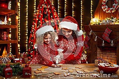 Merry Christmas and Happy Holidays. Cheerful cute curly little girl and her older sister in santas hats cooking Stock Photo