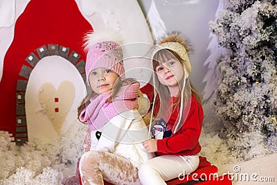 Merry Christmas, happy holidays. New Year. Little girls like to ride sleigh. Children sledges. Street fun for family Christmas. Wi Stock Photo