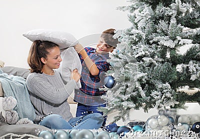 Merry christmas and happy holidays! sister and brother decorate the christmas tree. and they play by pillow fighting Stock Photo