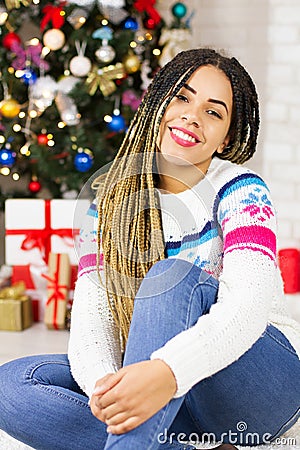 Merry Christmas, Happy New Year. Closeup african american young woman at home on Christmas Eve background, gift boxes, presents. Stock Photo