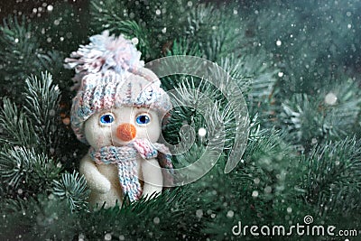 Merry Christmas and happy New year. A small toy snowman standing in the branches of spruce. Background with copy space Stock Photo