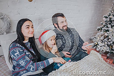 Merry Christmas and Happy New Year . Young family celebrating holiday at home. The Father is holding the remote from the Stock Photo