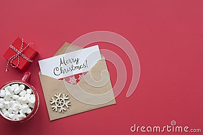 Merry Christmas red card top view. Envelope with wish, gift and mug of coffee on red background Stock Photo