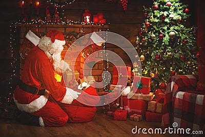 Merry Christmas! santa claus near the fireplace and tree with gi Stock Photo