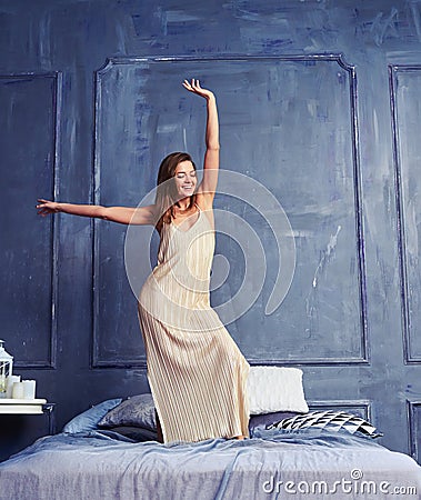 Merry female in a long nightgown standing with raised hand on th Stock Photo