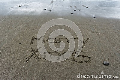 Merry Xmas written in the sand with wet sand behind Stock Photo