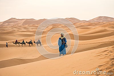 Merzouga, Morocco - APRIL 29 2019: MaroccanMoroccan standing in the sand in the Sahara Desert looking at the horizon Editorial Stock Photo