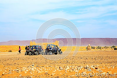 Merzouga, Morocco - Feb 26, 2016: back view on group of off-road pilots during a break in berber village on Morocco desert near M Editorial Stock Photo