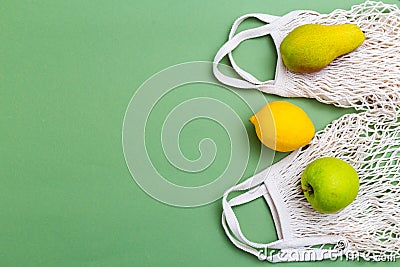 Mesh shopping bag with fruits on green background. BACK TO NATURE. Copy space Stock Photo