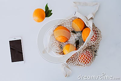 Mesh shopping beg with oranges and phone - nature friendly style Stock Photo