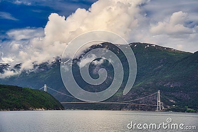 Mesmerizing view of a bridge over the river with a forested mountain on the background Stock Photo