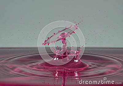 Mesmerizing pink water drop collision creating perfect symmetrical splash on smooth surface Stock Photo
