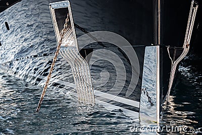 The mesmerizing reflection of the water on the glossy side of a huge yacht anchored, chrome details, chains and ropes to Stock Photo