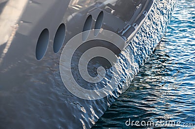 The mesmerizing reflection of the water on the glossy side of a huge yacht anchored, chrome details Stock Photo