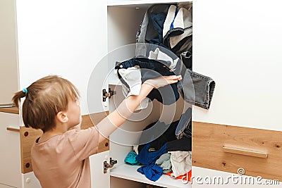 Mess in the wardrobe. Untidy clutter clothing closet. Boy takes clothes for a walk. Messy home kid`s room Stock Photo