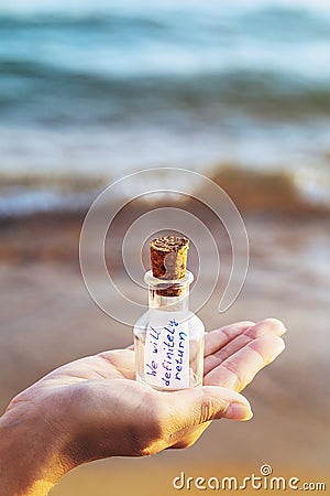 Message in a bottle with inscription: we will definitely return. Concept with copy space Stock Photo