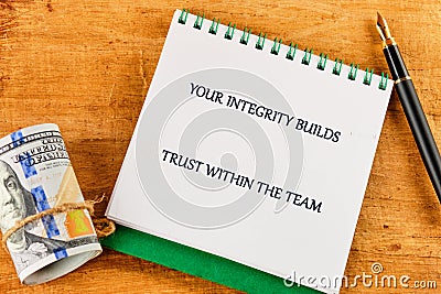 A message emphasizing integrity and trust appears on a notepad beside a bundle of cash and a pen, highlighting the Stock Photo