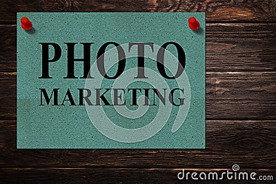 Messages `PHOTO MARKETING` written on green paper stands as an advertisement on a wooden surface Stock Photo