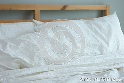 Messed bed with white pillow and blanket with natural light in bedroom in the morning Stock Photo