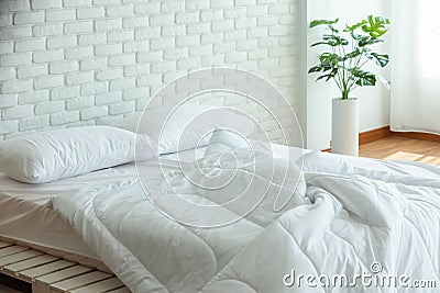 Messed bed with white pillow and blanket with natural light Stock Photo