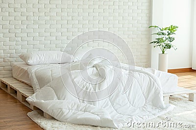 Messed bed with white pillow and blanket with natural light Stock Photo