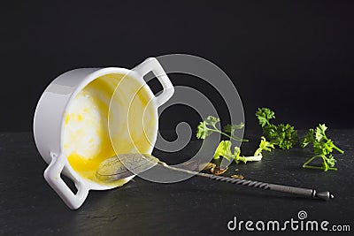 Messthetics aesthetic concept. A photo of dirty empty ceramic bowl, spoon and some parsley. Porridge, pumpkin cream soup leftovers Stock Photo