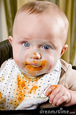 Messy baby wearing bib after eating solid food Stock Photo