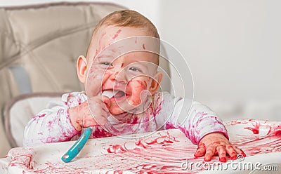 Messy and dirty baby is eating from spoon Stock Photo