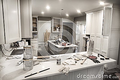 Messy home kitchen during remodeling with cabinet doors open cluttered with paint cans, tools and dirty rags Stock Photo