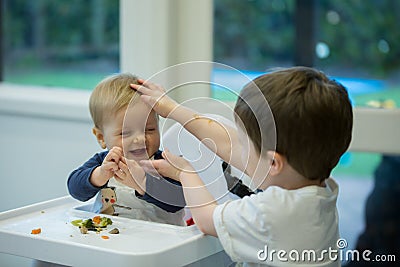 Messy kids - siblings being rough with baby Stock Photo