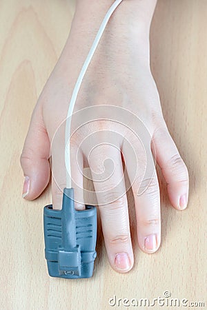 Pulse Oxymeter on a finger, isolated on a wood background Stock Photo