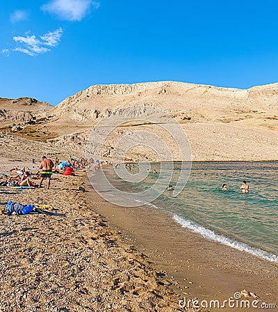 People on amazing sandy beach surrounded by rocky hills. Rucica beach on Pag island in Croatia. Editorial Stock Photo