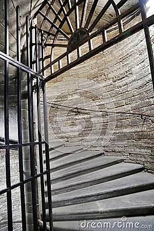 Metal antique spiral staircase with handrails in a stone tower. Stock Photo