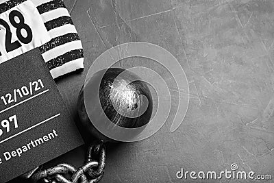 Metal ball with chain, prison uniform and mugshot letter board on grey table, flat lay. Space for text Stock Photo