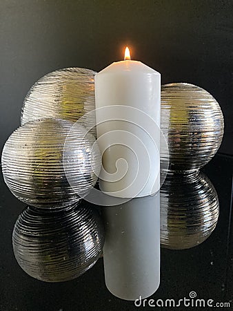 3 metal balls reflected in a glass table with candle Stock Photo