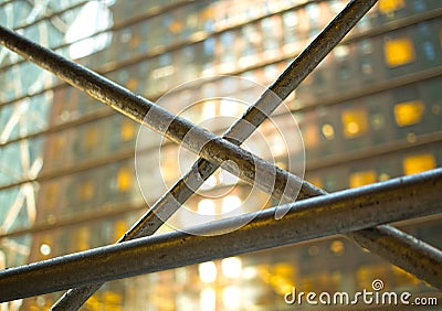 Metal bars in front of a glass building with yellow glowing windows Stock Photo